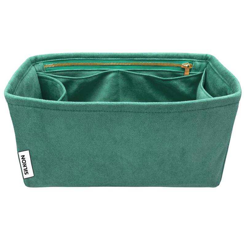 May include: A teal-colored handbag organizer with multiple compartments and a zippered top. The organizer is made of a soft, suede-like material and features a gold-colored zipper and the brand name "SILKON" on a white label.