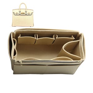 May include: Beige felt bag organizer with multiple compartments and a zippered closure. The organizer is designed to fit inside a larger handbag.