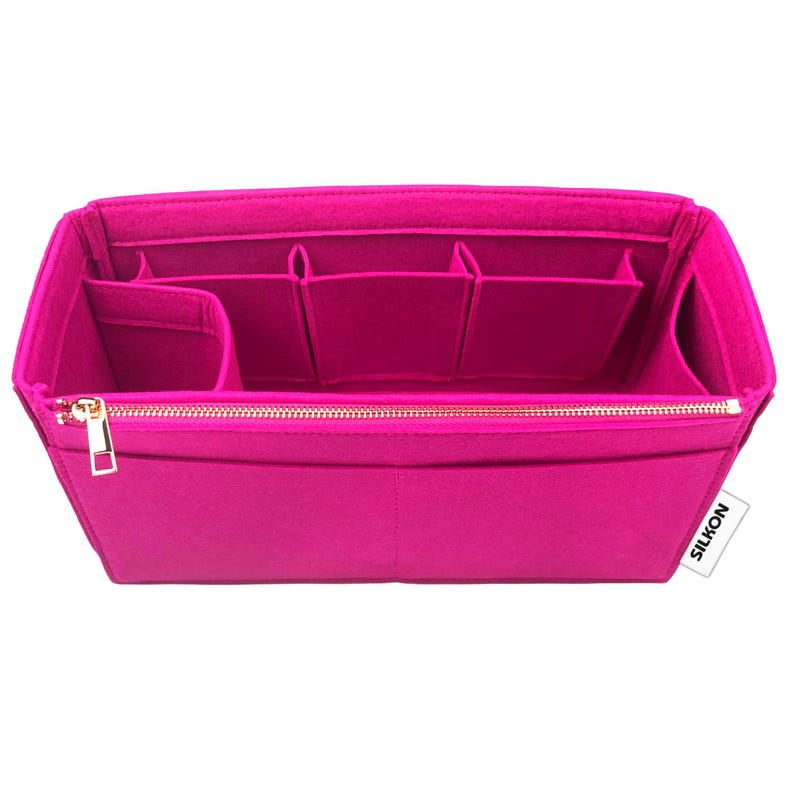 May include: A bright pink felt handbag organizer with multiple compartments and a gold zipper closure. The organizer has various pockets and sections for storing items. The brand name "SILKON" is visible on the side.