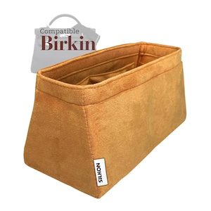 Puede incluir: Un organizador de bolso de color marrón claro con múltiples compartimentos. El organizador es rectangular con forma trapezoidal y está hecho de un material suave similar al ante. El texto "SILKON" está impreso en una etiqueta blanca en el lateral. El texto "Compatible Birkin" está en el fondo.