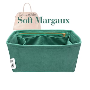 Könnte beinhalten: Ein tealfarbener Handtaschen-Organizer mit mehreren Fächern und einem goldenen Reißverschluss. Der Organizer ist mit "SILKON" beschriftet und für eine "Soft Margaux" Handtasche konzipiert. Im Hintergrund ist eine hellfarbige Handtasche abgebildet.