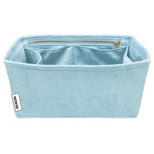 May include: A light blue felt bag organiser with multiple compartments and a zipped top closure. The organiser has a rectangular shape and a label that reads "SILKON". The interior is a lighter shade of blue.