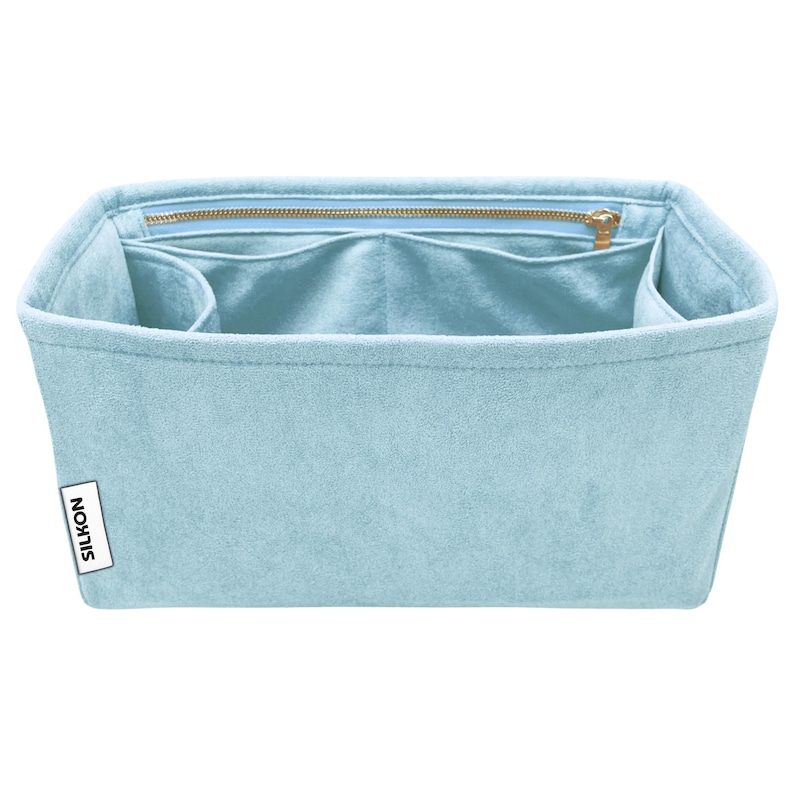 May include: A light blue felt bag organizer with multiple compartments and a zippered top closure. The organizer has a rectangular shape and a label that reads "SILKON". The interior is a lighter shade of blue.