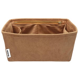 May include: A brown handbag organizer with multiple compartments and a zippered top closure. The organizer is made of a soft, suede-like material and features the brand name "SILKON" on a small white label.