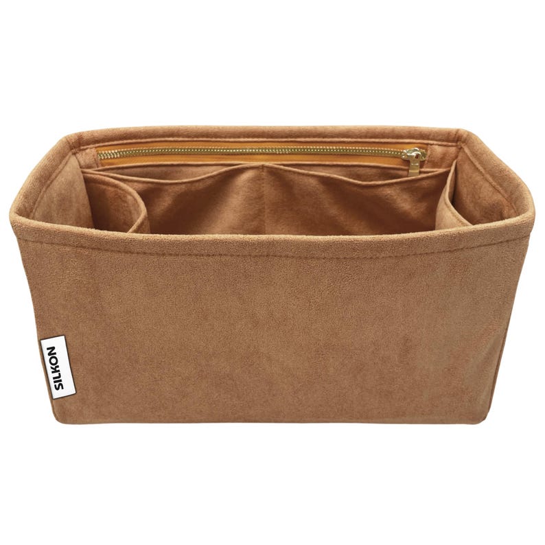 May include: A brown handbag organizer with multiple compartments and a zippered top closure. The organizer is made of a soft, suede-like material and features the brand name "SILKON" on a small white label.