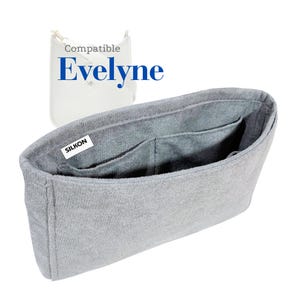 May include: A gray bag organizer with multiple pockets, designed to fit inside a handbag. The organizer has the word "SILKON" on a white label. The text "Compatible Evelyne" is also visible in the image.