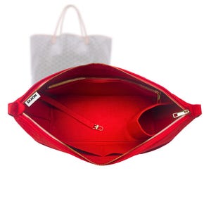 May include: A vibrant red handbag organiser with a gold zip and multiple internal pockets. The organiser has a long strap with a gold clasp and the word "SILKON" is printed on a white label.