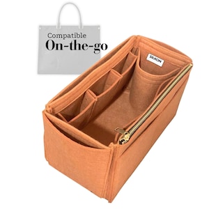 Op de afbeelding: Een perzikkleurige tassenorganizer met meerdere compartimenten en een gouden rits. De organizer is ontworpen om in een grotere tas te passen en heeft de tekst "Compatible On-the-go". De merknaam "SILKON" is zichtbaar.