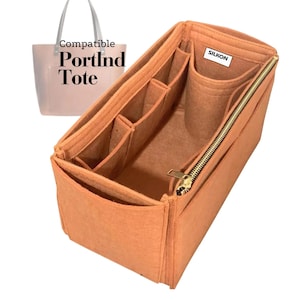 Peut inclure: Un organisateur de sac en feutre orange avec plusieurs compartiments et une fermeture éclair dorée. L'organisateur est conçu pour s'adapter à l'intérieur d'un sac fourre-tout, comme l'indique le texte "Compatible PortInd Tote". La marque "SILKON" est visible.