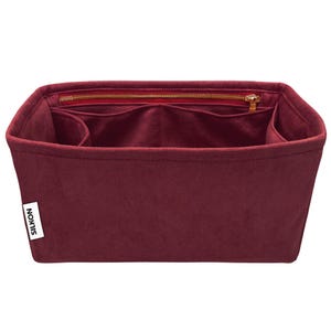 May include: A burgundy felt handbag organizer with multiple compartments and a zippered top closure. The organizer has a rectangular shape and a label that reads "SILKON". The interior features several pockets for organization.