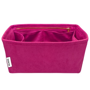 May include: A vibrant fuchsia handbag organiser with several internal compartments and a zipped top. The organiser is made from a soft, felt-like material and has the brand name "SILKON" on a white label.