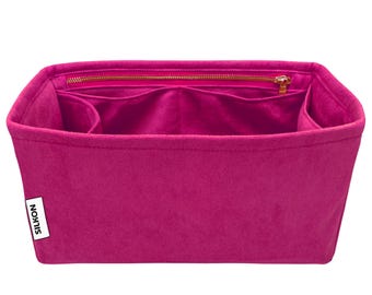 Op de afbeelding: Een fuchsia handtassenorganizer met meerdere compartimenten en een ritssluiting aan de bovenkant. De organizer is gemaakt van een zacht, viltachtig materiaal en heeft de merknaam "SILKON" op een wit label.