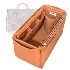 May include: An orange felt bag organizer with multiple compartments and a gold zipper. The organizer has several pockets of varying sizes and a label that reads "SILKON". A sketch of a handbag is in the background.