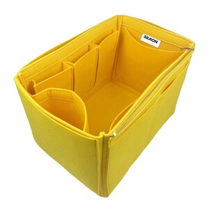 May include: A bright yellow felt bag organizer with multiple compartments and a zippered closure. The organizer has several pockets of varying sizes and a label that reads "SILKON".