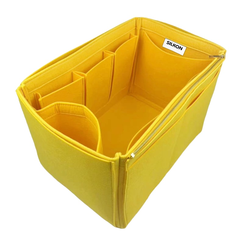 May include: A bright yellow felt bag organizer with multiple compartments and a zippered closure. The organizer has several pockets of varying sizes and a label that reads "SILKON".