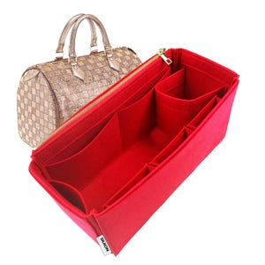 Pode incluir: Uma caneca de cerâmica branca com uma alça preta e o texto "But First, Coffee" em preto, com uma fonte manuscrita. A caneca está sobre uma superfície branca.