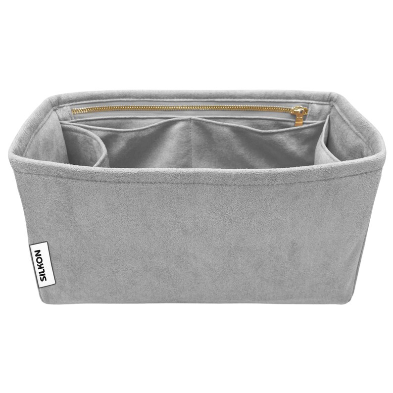 May include: A gray bag organizer with multiple compartments and a zippered top closure. The organizer has a rectangular shape and is made of a soft, suede-like material. The brand name "SILKON" is visible on a white label.