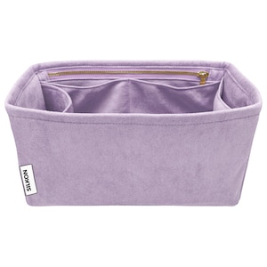 May include: A lavender-colored bag organizer with multiple compartments and a zippered top closure. The organizer is made of a soft, suede-like material and features a small white label with the word "SILKON" printed on it.