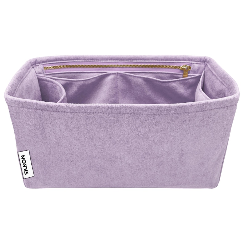May include: A lavender-colored bag organizer with multiple compartments and a zippered top closure. The organizer is made of a soft, suede-like material and features a small white label with the word "SILKON" printed on it.