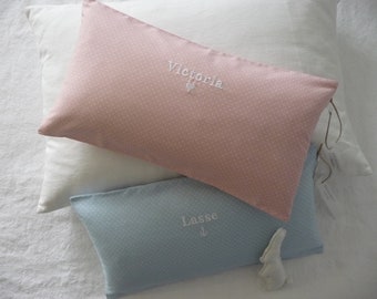 May include: Two decorative pillows with white polka dots. The pink pillow has the name "Victoria" embroidered on it. The blue pillow has the name "Lasse" embroidered on it.