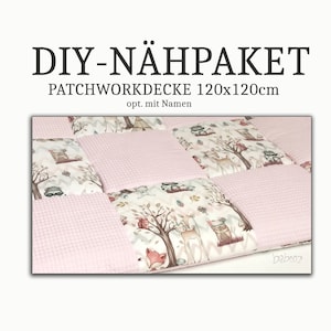 Könnte beinhalten: Ein Patchwork-Quilt mit Waldtiermotiv, mit Hirschen, Füchsen und Waschbären. Der Quilt hat rosa Quadrate und Quadrate mit einem Waldaufdruck. Der Text "DIY-NÄHPÄKET PATCHWORKDECKE 120x120cm" steht oben. Misst 120x120cm.