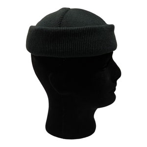 May include: A dark green beanie with a ribbed texture. The beanie is folded up at the top, creating a rounded shape.