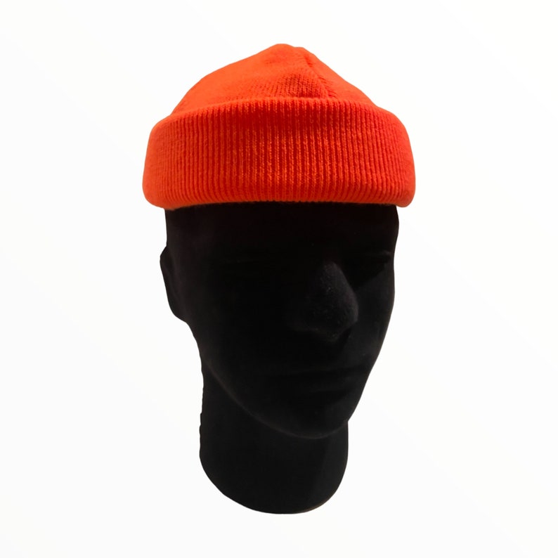 May include: A bright orange beanie with a fold-over cuff. The beanie is made of a soft, knitted fabric.