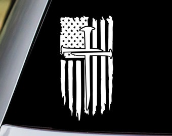 May include: A white vinyl decal of a distressed American flag with a cross made of two hammers. The cross is centered on the flag.