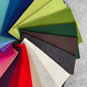 May include: A variety of felt fabric swatches in different colors, including teal, blue, green, brown, gray, white, beige, red, pink, and purple. The swatches are arranged in a fan shape.