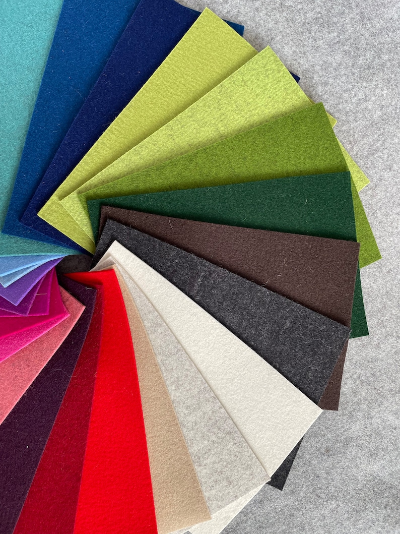 May include: A variety of felt fabric swatches in different colors, including teal, blue, green, brown, gray, white, beige, red, pink, and purple. The swatches are arranged in a fan shape.