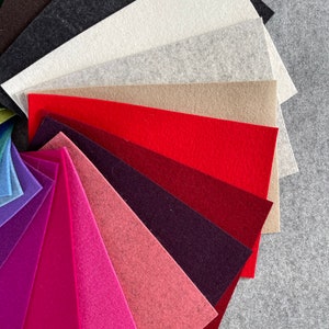 May include: A fan-shaped arrangement of felt fabric swatches in various colors, including brown, black, white, gray, beige, red, burgundy, pink, and purple.