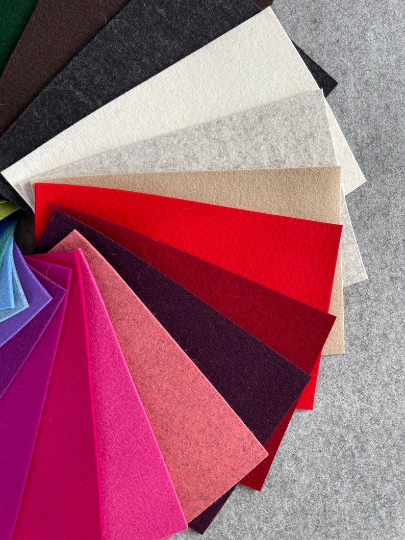 May include: A fan-shaped arrangement of felt fabric swatches in various colors, including brown, black, white, gray, beige, red, burgundy, pink, and purple.