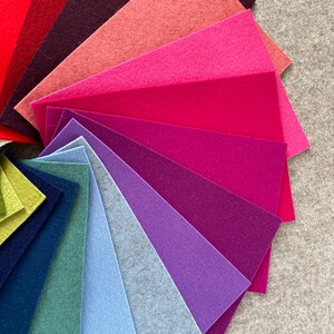 May include: A fan-shaped arrangement of felt fabric swatches in various shades of red, pink, purple, blue, and green. The swatches are arranged in a gradient from red to green.