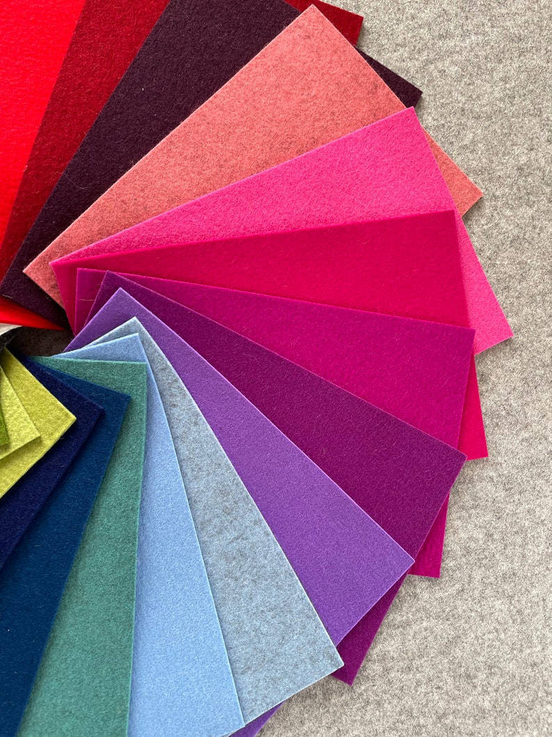 May include: A fan-shaped arrangement of felt fabric swatches in various shades of red, pink, purple, blue, and green. The swatches are arranged in a gradient from red to green.