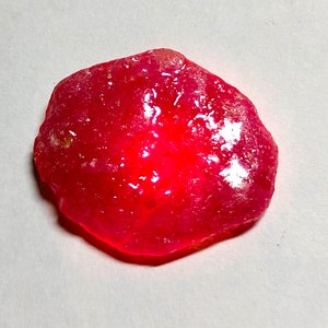Op de afbeelding: Een grote, ruwe, rode edelsteen met een glanzend, gepolijst oppervlak.