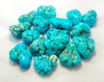 May include: A collection of turquoise stones, each with a unique shape and pattern of veins. The stones are a vibrant blue-green color and have a smooth, polished finish.