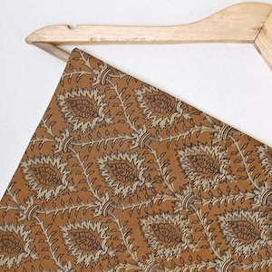 May include: A brown fabric with a beige and black floral pattern. The fabric is draped over a wooden hanger.