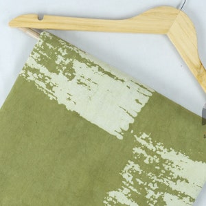 May include: Green fabric with a white tie-dye pattern. The fabric is draped over a wooden hanger.