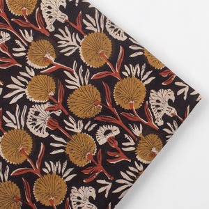 Può includere: Tessuto piegato con un motivo floreale ripetuto. Il design presenta grandi fiori rotondi color beige, foglie bianche e steli marrone-rossastro su sfondo nero. Il tessuto è probabilmente cotone o lino, adatto a vari progetti.