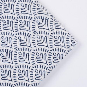 Pode incluir: Tecido branco com um padrão repetitivo de formas de folhas azul marinho dentro de molduras quadradas. O tecido está dobrado, mostrando a continuidade do padrão. Ideal para projetos de artesanato, com um design botânico moderno.