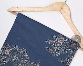 May include: A blue cotton fabric with a white and green floral pattern and small pink birds. The fabric is hanging on a wooden hanger.