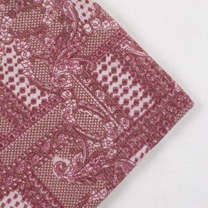 May include: A pink and white fabric with a paisley pattern. The fabric has a textured, almost quilted look.