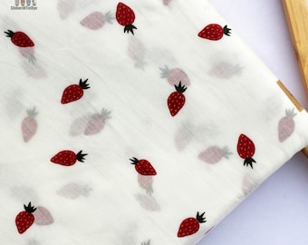 May include: White fabric with a repeating pattern of red strawberries. The fabric is folded and draped over a wooden hanger.