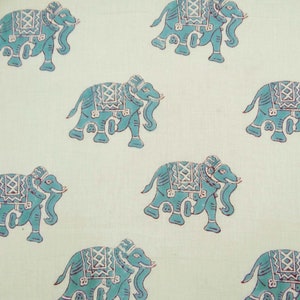 May include: A white fabric with a repeating pattern of blue elephants. The elephants have intricate designs on their backs and are facing to the right.