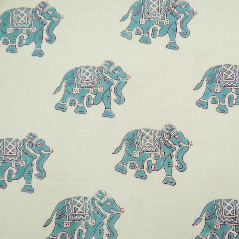 May include: A white fabric with a repeating pattern of blue elephants. The elephants have intricate designs on their backs and are facing to the right.