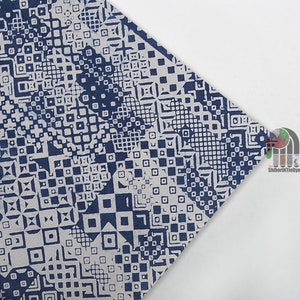 May include: A white fabric with a blue geometric pattern. The pattern is made up of squares, rectangles, and other shapes. The fabric is folded in half.