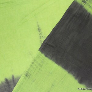 Op de afbeelding: Een groene en zwarte tie-dye stof met een verloop effect. De stof is zacht en licht, waardoor het perfect is voor een verscheidenheid aan projecten.