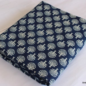 May include: A folded piece of blue cotton fabric with a white floral pattern. The fabric is folded in thirds and has a white background with a blue floral pattern.