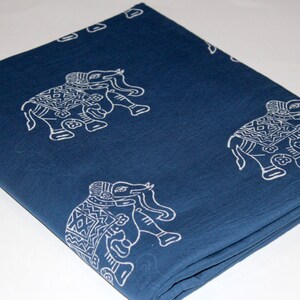 May include: A folded blue cotton fabric with a white elephant print. The fabric is folded in thirds and has a blue background with white elephants printed on it.