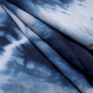 May include: Blue and white tie-dye fabric with a soft, textured feel. The fabric is folded and draped, showcasing the intricate pattern.